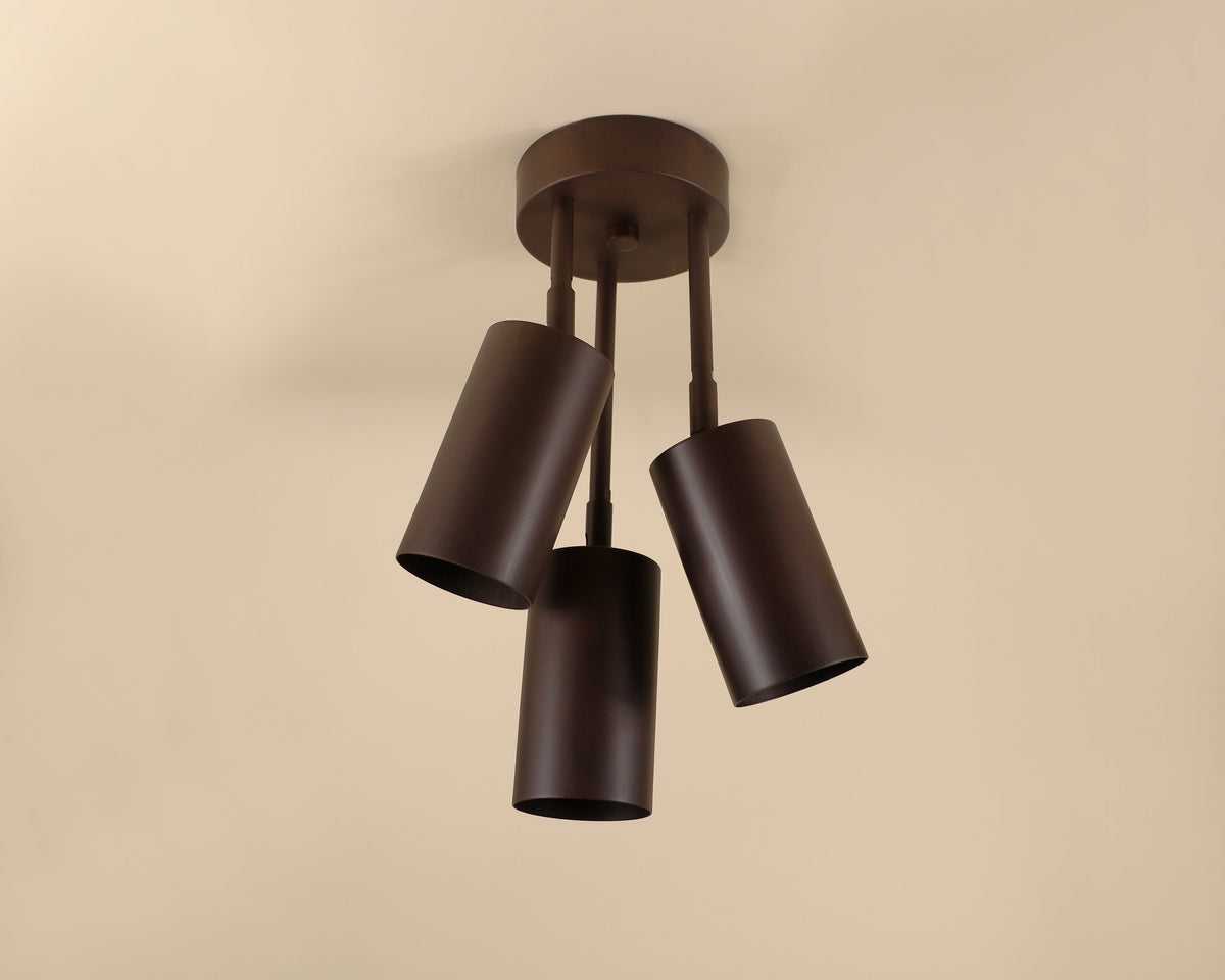Modern ceiling light fixture with four cylindrical shades on a beige background