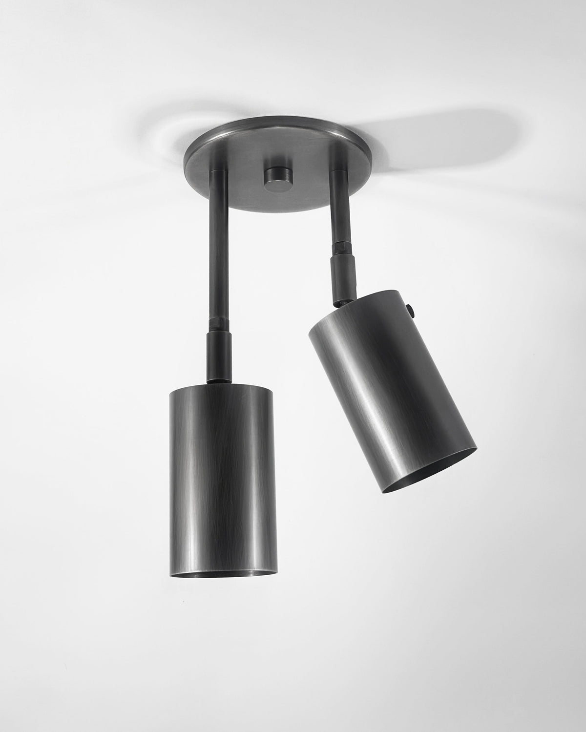 Two cylindrical brass ceiling light fixtures mounted on a ceiling, with adjustable directions for lighting.