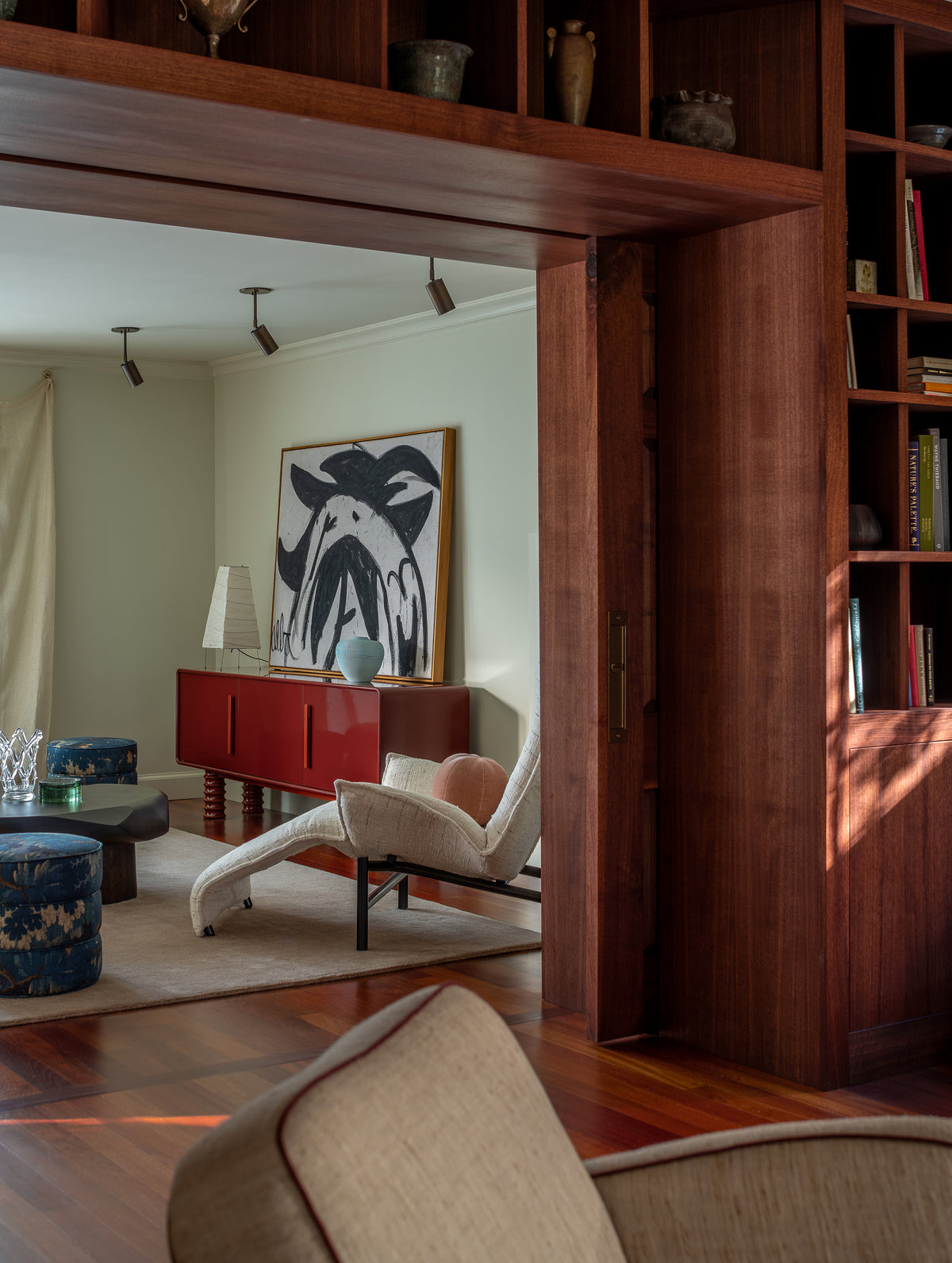 Living room with wooden bookshelf, red sideboard, and modern furniture.