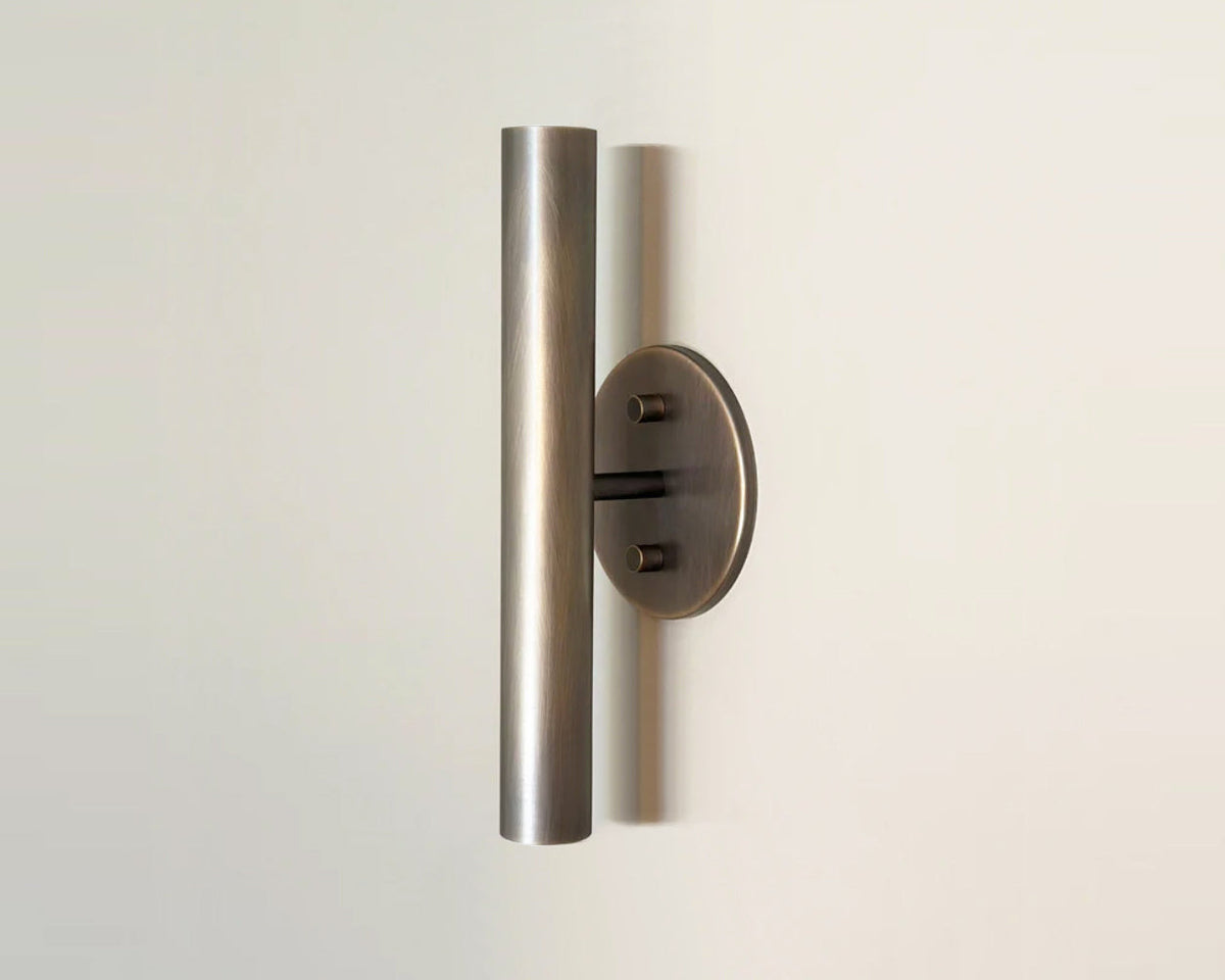 The Miro 2 - Inset Bulbs - 12" by Long Made Co. is a modern ADA compliant up down wall sconce with a vertical cylindrical metal shade and round base, shown mounted on a plain light-colored wall.