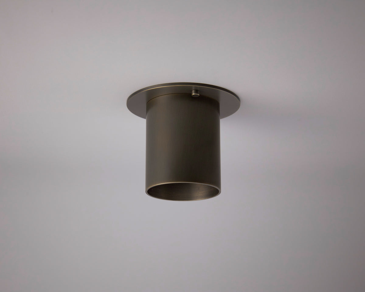The Highland Flush Spot - Stocky by Long Made Co. is a cylindrical, dark metal ceiling light with a wide rim, handmade in Texas and installed as flush monopoint lighting on a plain white ceiling.