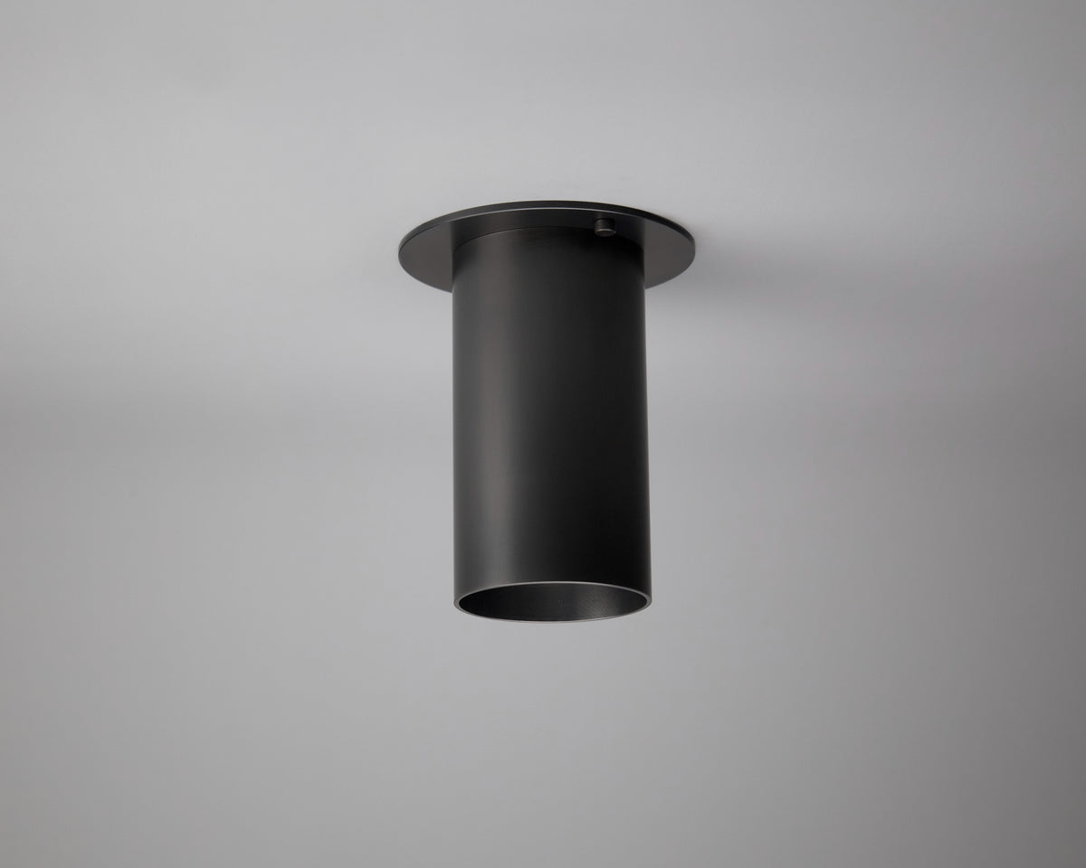 The Highland Flush Spot by Long Made Co., a black monopoint lighting fixture with a flat circular base, is mounted on a white ceiling and photographed from below.