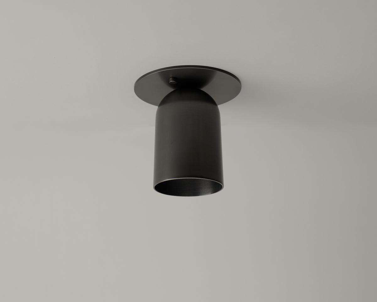 A Long Made Co. Campana Flush Spot, a matte black cylindrical flush mount ceiling downlight, is installed on a plain white ceiling.