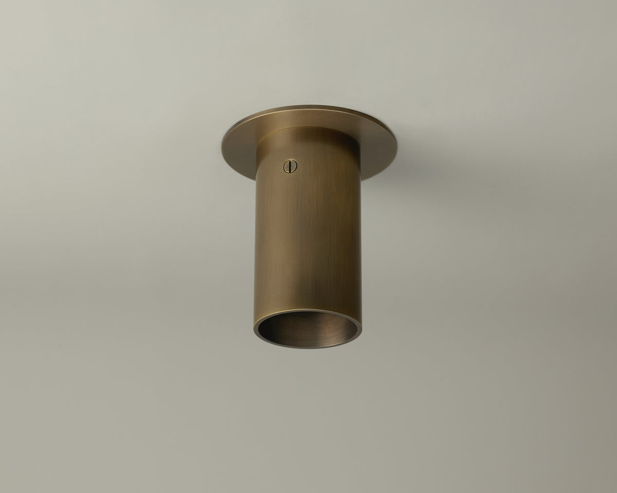 The Beau Laiton Flush Spot by Long Made Co. is a cylindrical solid brass fixture with a brushed finish, offering minimalist style and flush mounting for a seamless look on white ceilings.