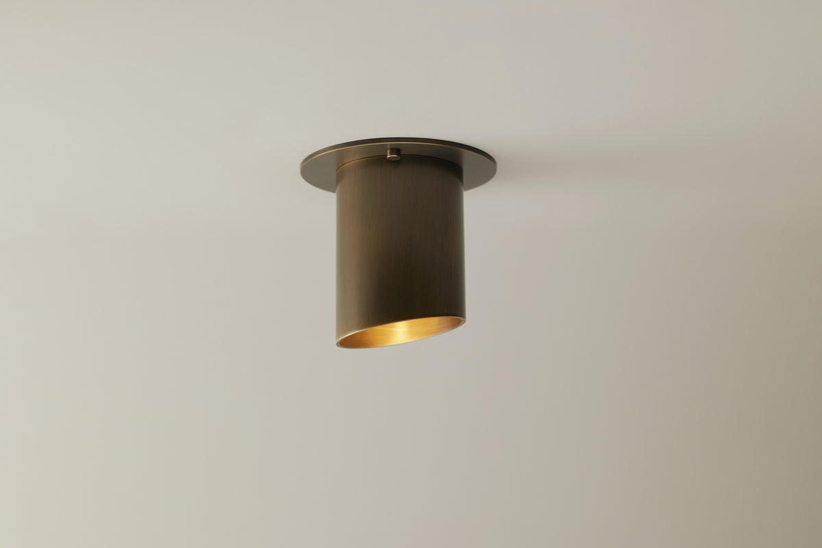 The Highland Angle Spot - Stocky by Long Made Co. is a modern, cylindrical bronze flush monopoint ceiling light, handmade in Texas for a warm glow on a plain white ceiling.