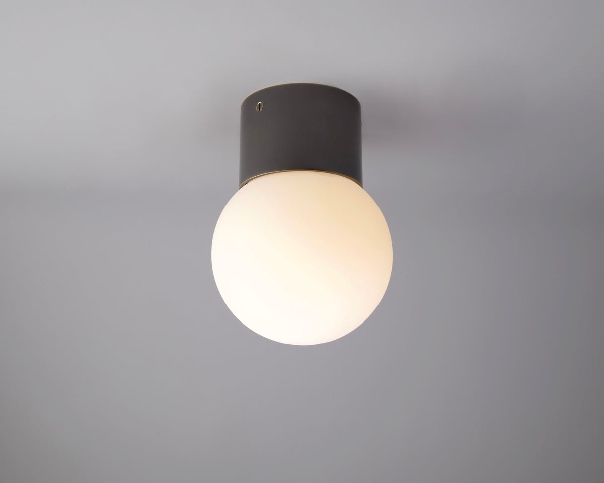 The Beau Laiton Trimless Sphere by Long Made Co. is a modern minimalist luxury fixture featuring a round white frosted glass globe and matte black cylindrical base, elegantly mounted on a light gray ceiling.