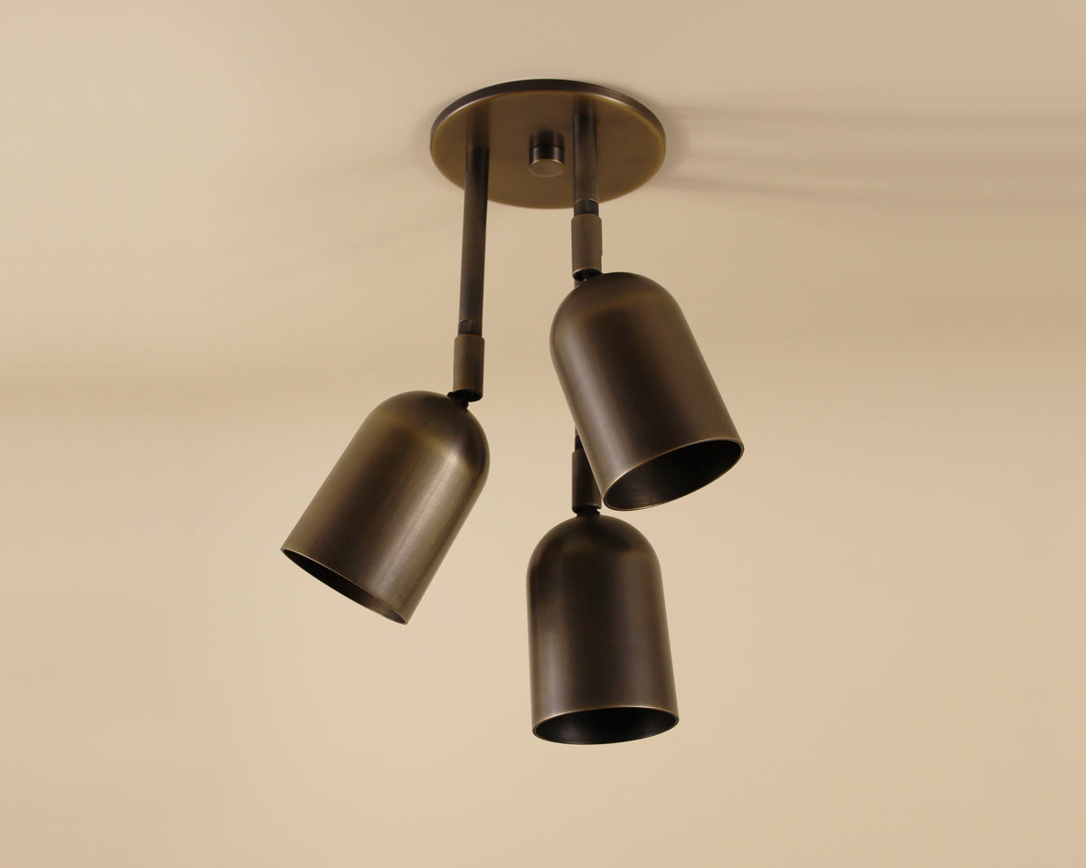 Ceiling light fixture with three metal shades on a beige background