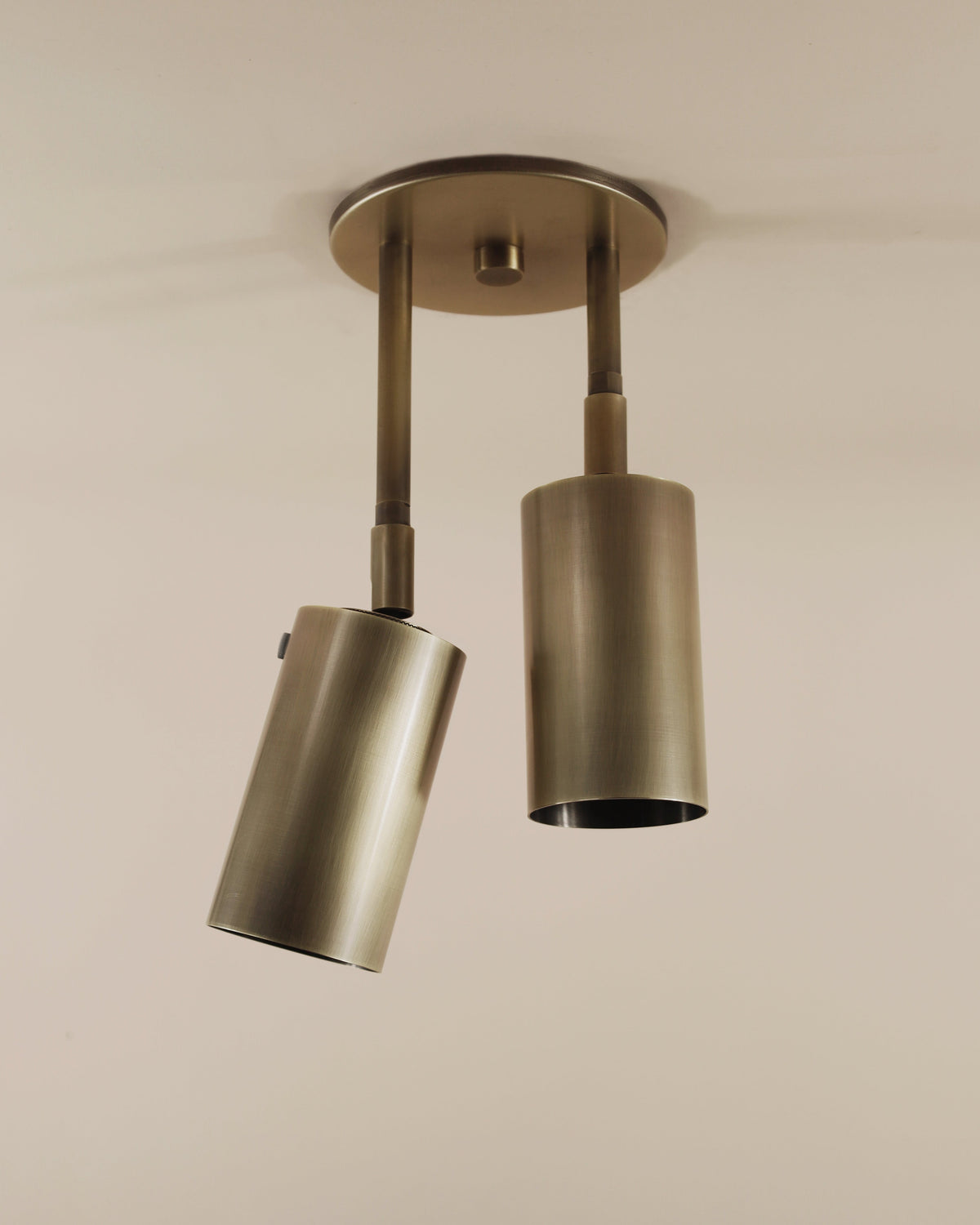 Double Drop Spot - Brass Cylinder Series Light in Light Oxidized Brass on tan background.