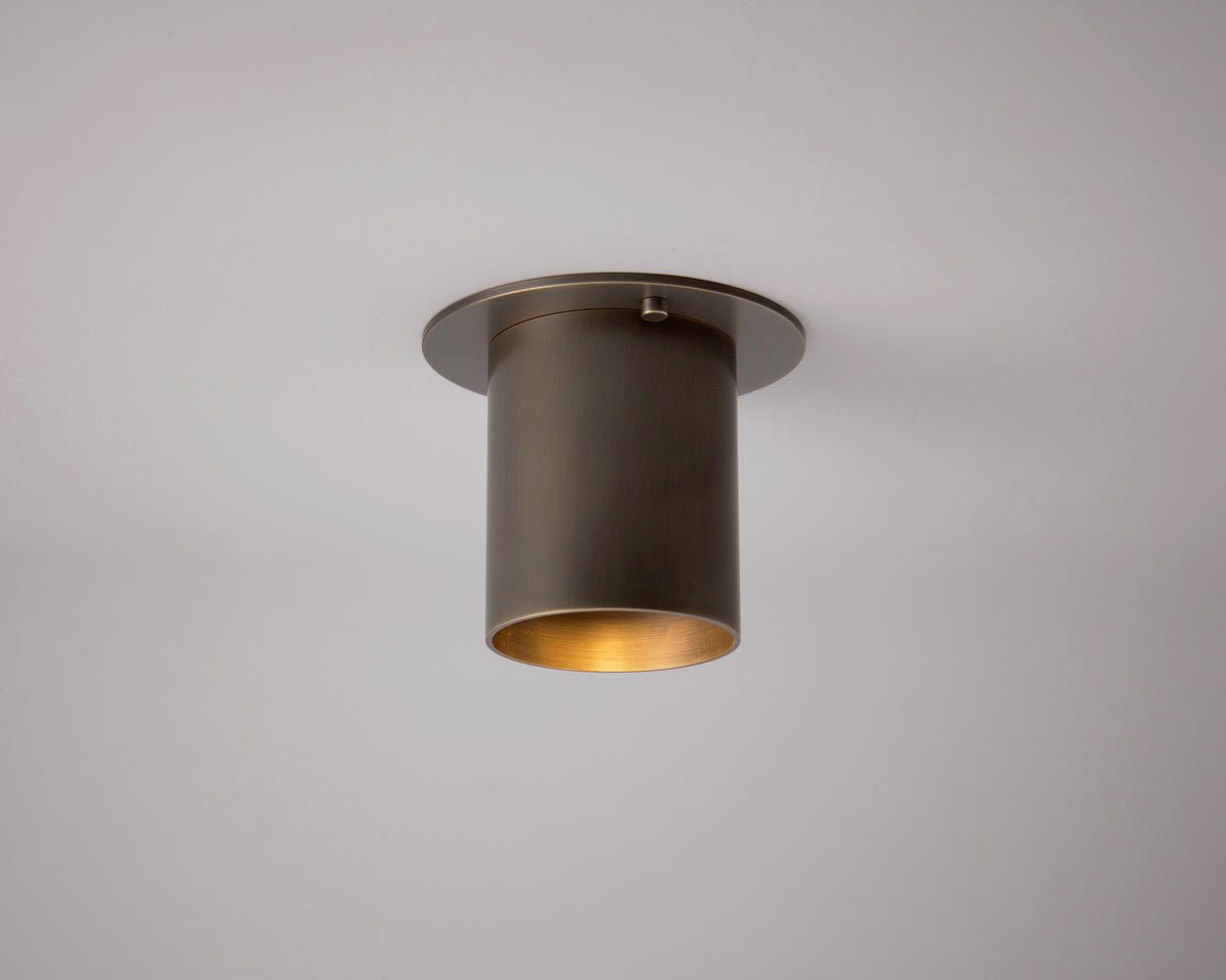 The Highland Flush Spot - Stocky by Long Made Co. is a modern, cylindrical ceiling light with a metallic finish, expertly handmade in Texas to softly illuminate your space and add artisanal charm.