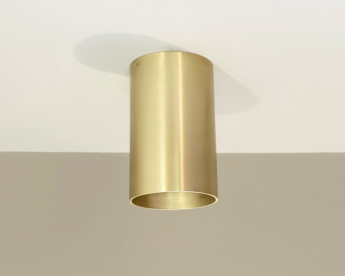 The Long Made Co. Beau Laiton XL Trimless Downlight - Ketra S30 Compatible, a gold-toned cylindrical solid brass fixture, is installed on a white ceiling and casts a faint shadow above.