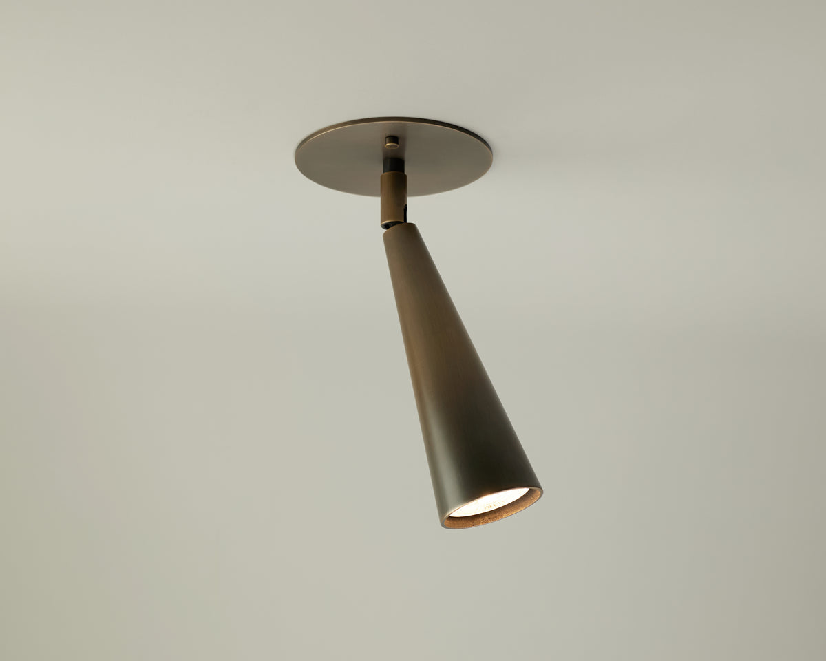 The Pine Adjustable Spot by Long Made Co. is a modern, cone-shaped directional ceiling downlight with a matte black finish, mounted on a round base against a plain white ceiling.