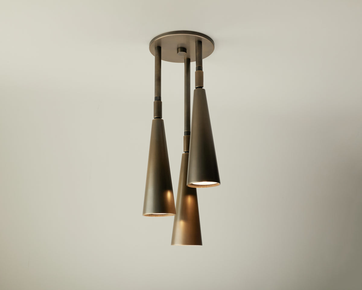 Three metallic, cone-shaped Pine Cascade Drop Spot pendant lights by Long Made Co. hang from a round ceiling mount at varying heights against a plain white ceiling.