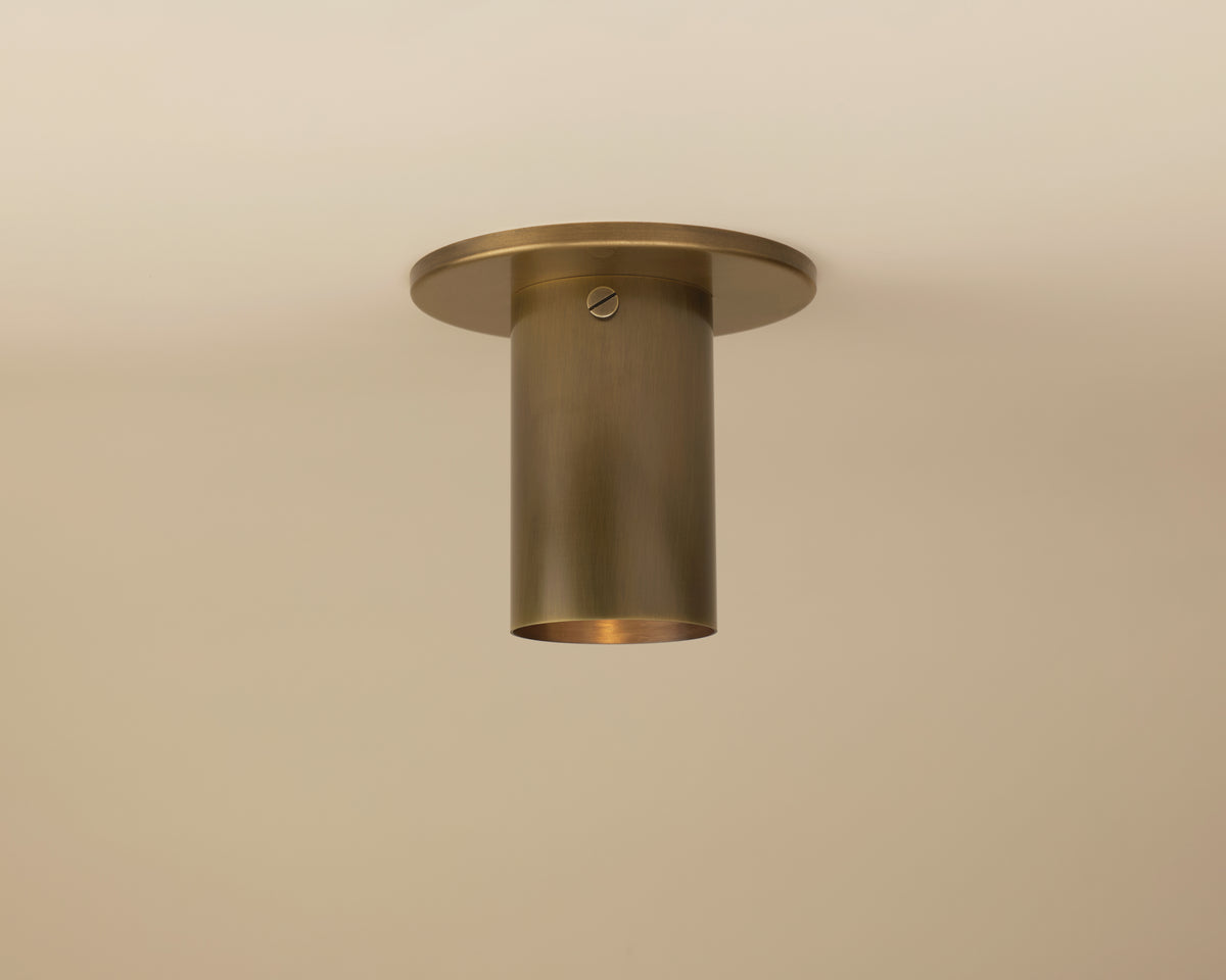 The Long Made Co. Brass Cylinder Flush Spot is a minimalist brass ceiling light with a round base, mounted flush to the ceiling. Its visible screw detail makes it ideal for mid-century modern interiors.