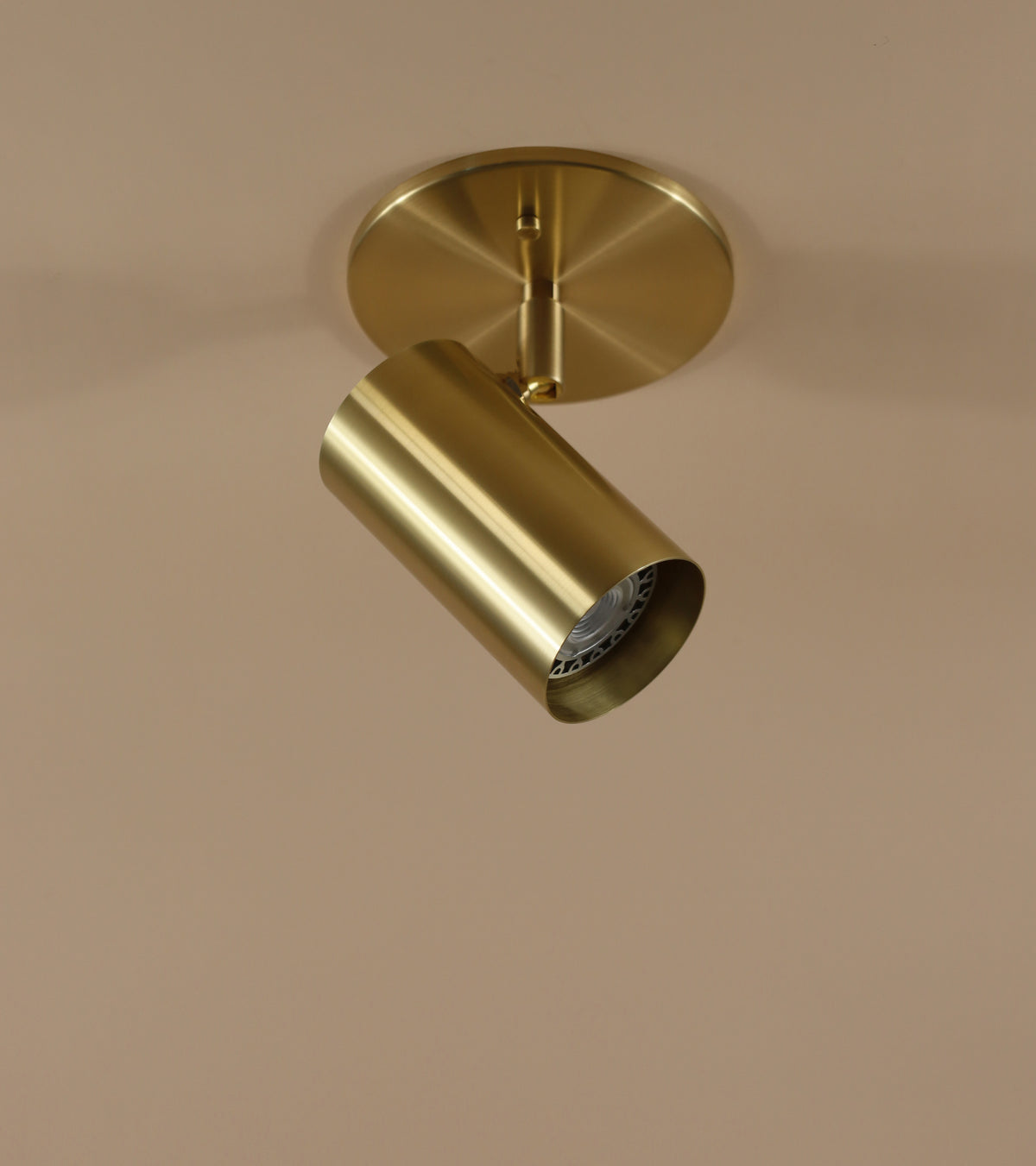 The Long Made Co. Brass Cylinder Adjustable Spot – Side Mount features a gold-tone cylindrical design on a round base, mounted against a light beige background and highlighting sleek mid-century modern style.