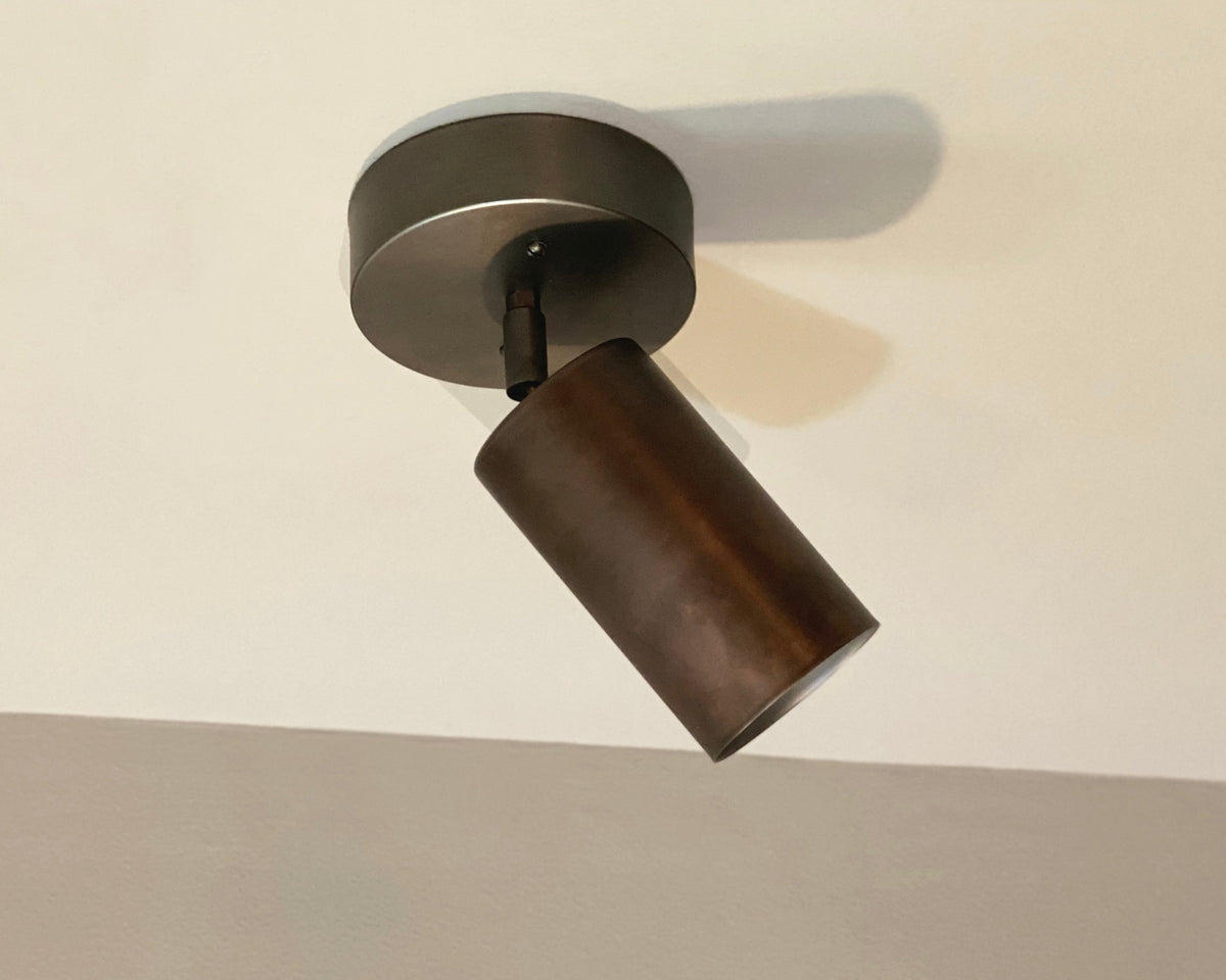 A bronze oxidized steel cove adjustable chunky spot light fixture mounted on a wall.